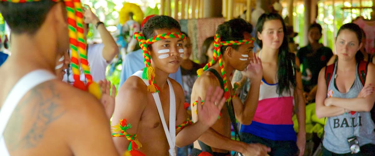 A group of people in traditional attire with colorful headdresses, playing drums.