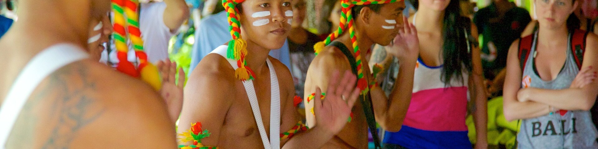 A group of people in traditional attire with colorful headdresses, playing drums.