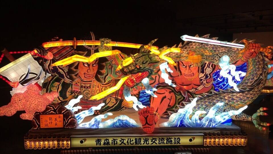 A large illuminated dragon sculpture with traditional Chinese characters and a warrior figure.