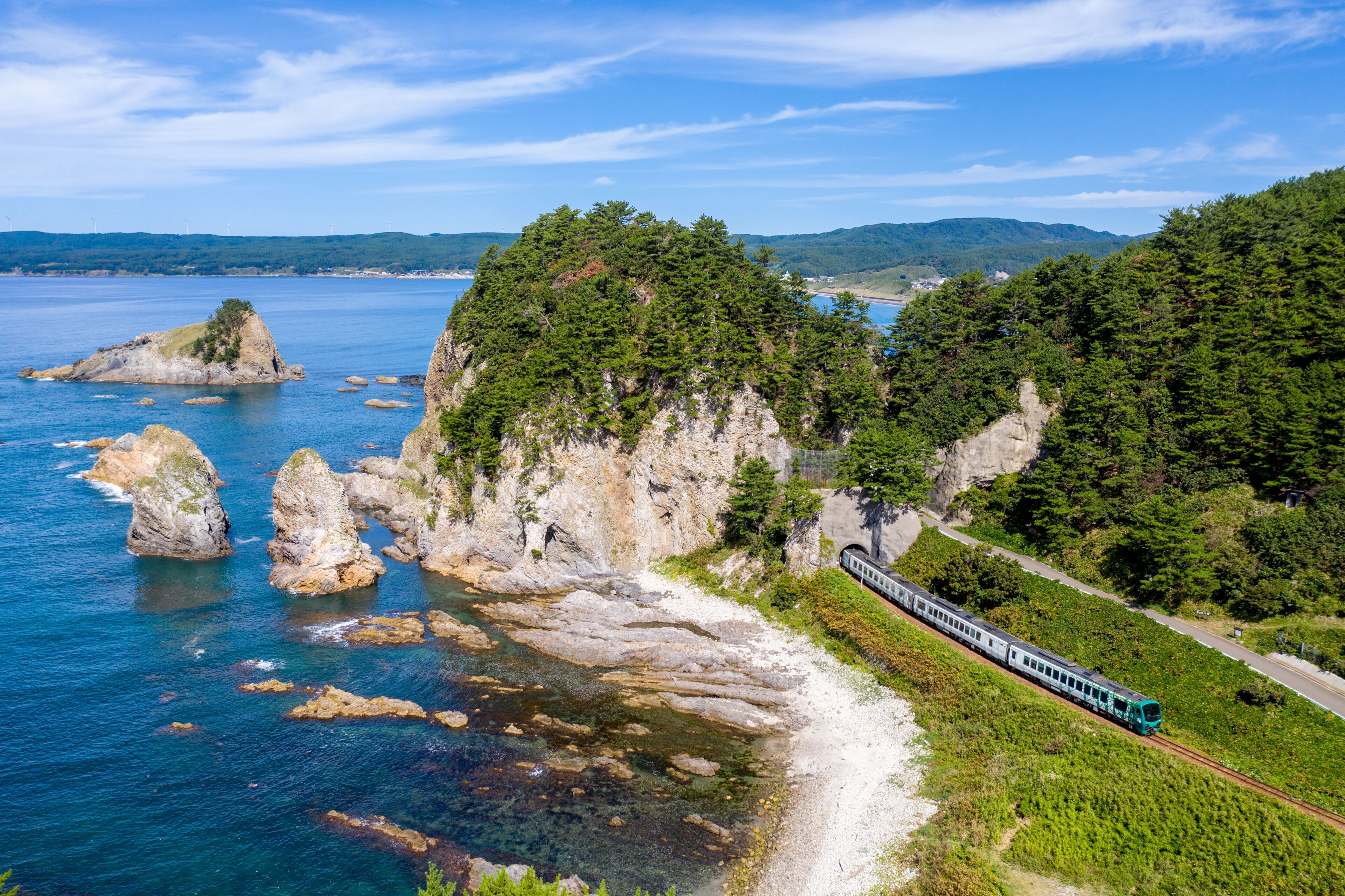 青森県 深浦町の海岸線にあるガンガラ穴付近を通過する五能線のリゾート列車を俯瞰撮影