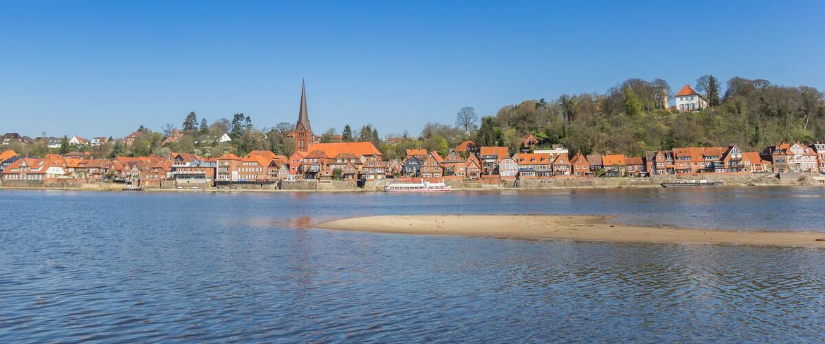 A riverside town with historic buildings and a church spire.