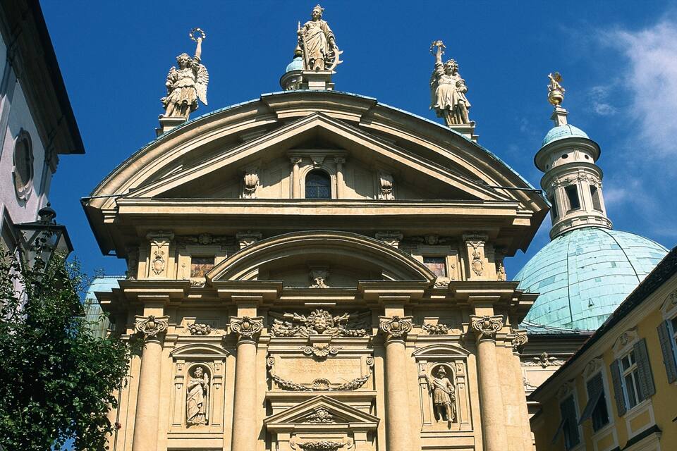 Ein historisches Gebäude mit aufwendiger Architektur, einschließlich Statuen und einer Kuppel.