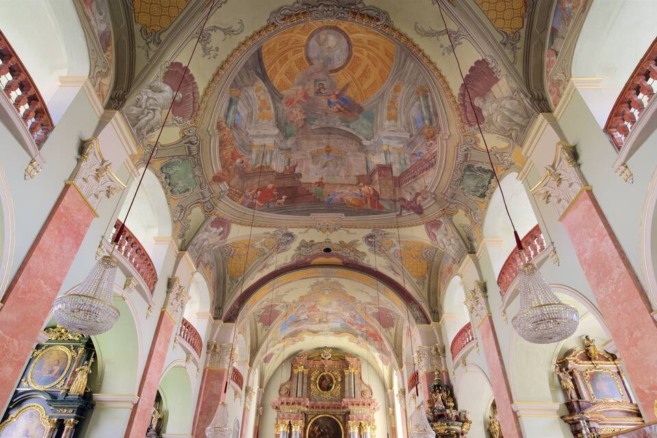 Ein prunkvolles Kircheninnere mit hoher Decke, aufwendigen Fresken und einem zentralen Altar.