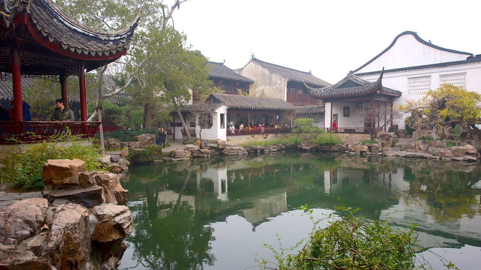 A traditional Chinese courtyard with a pond, buildings, and a pavilion.