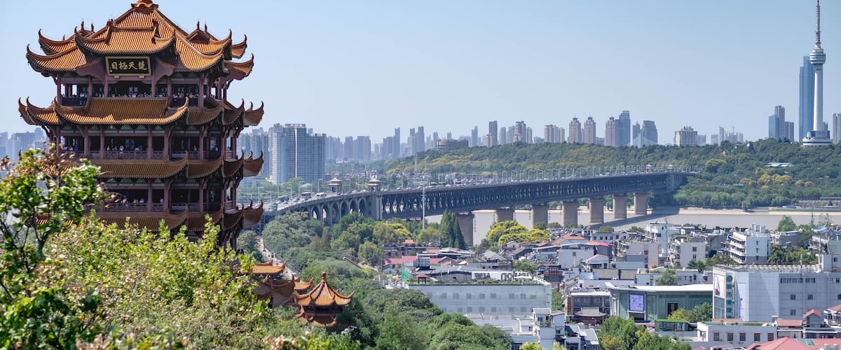 A traditional pagoda with multiple tiers, a modern city skyline, and a bridge spanning a river.