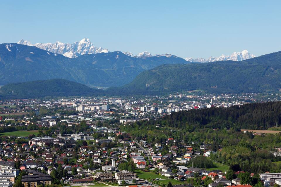 Eine Stadt eingebettet zwischen Bergen mit schneebedeckten Gipfeln im Hintergrund.