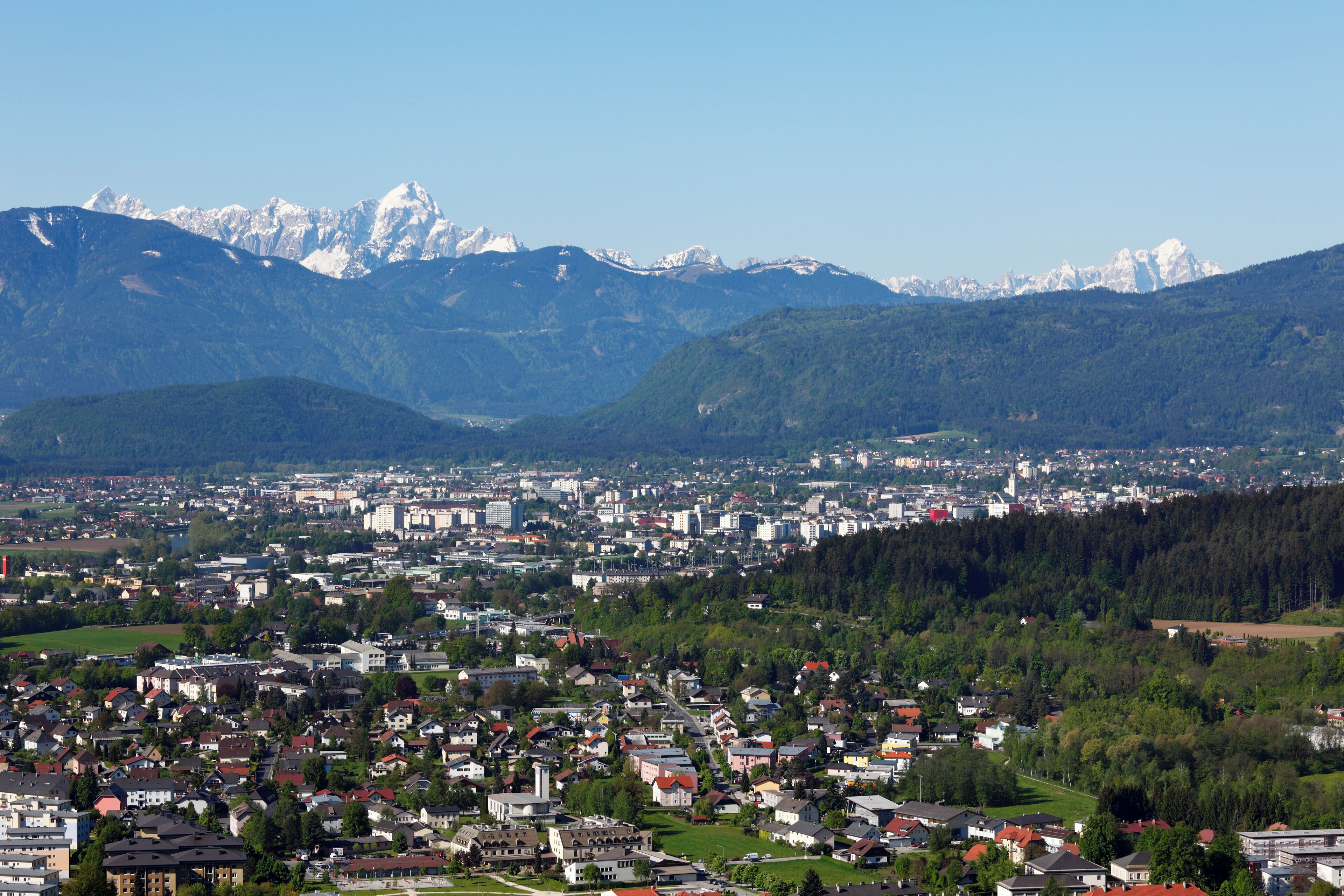 A town nestled between mountains with snow-capped peaks in the background.