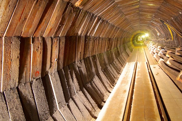 A wooden tunnel with a wooden bench along the side.