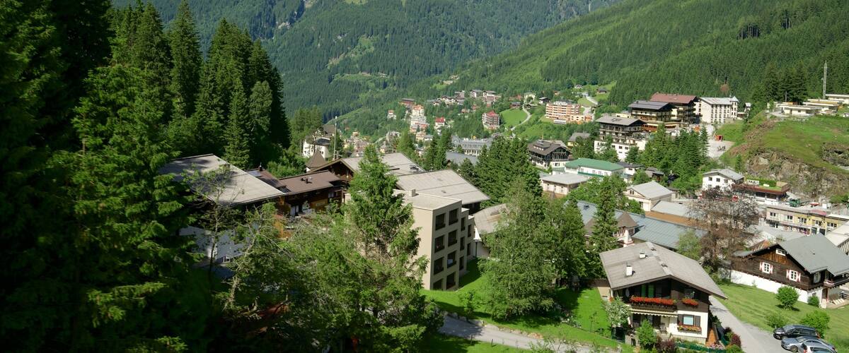 A mountainous village with dense forests, traditional houses, and a backdrop of green hills.