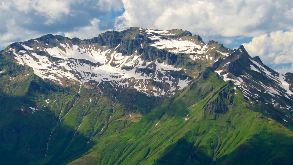 A mountain with snow patches and green slopes.