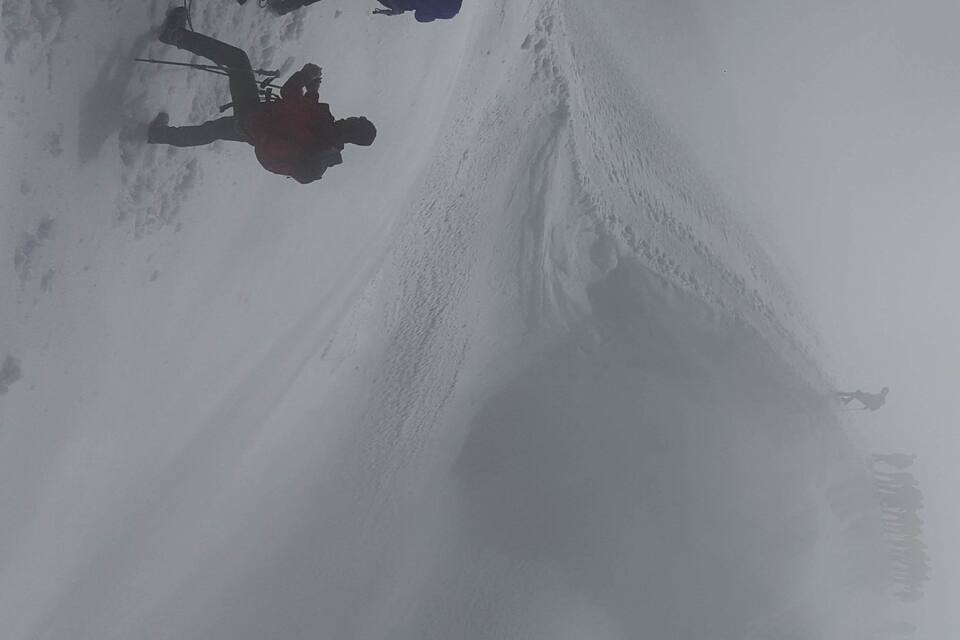 Paisaje nevado con una persona esquiando por una pendiente.