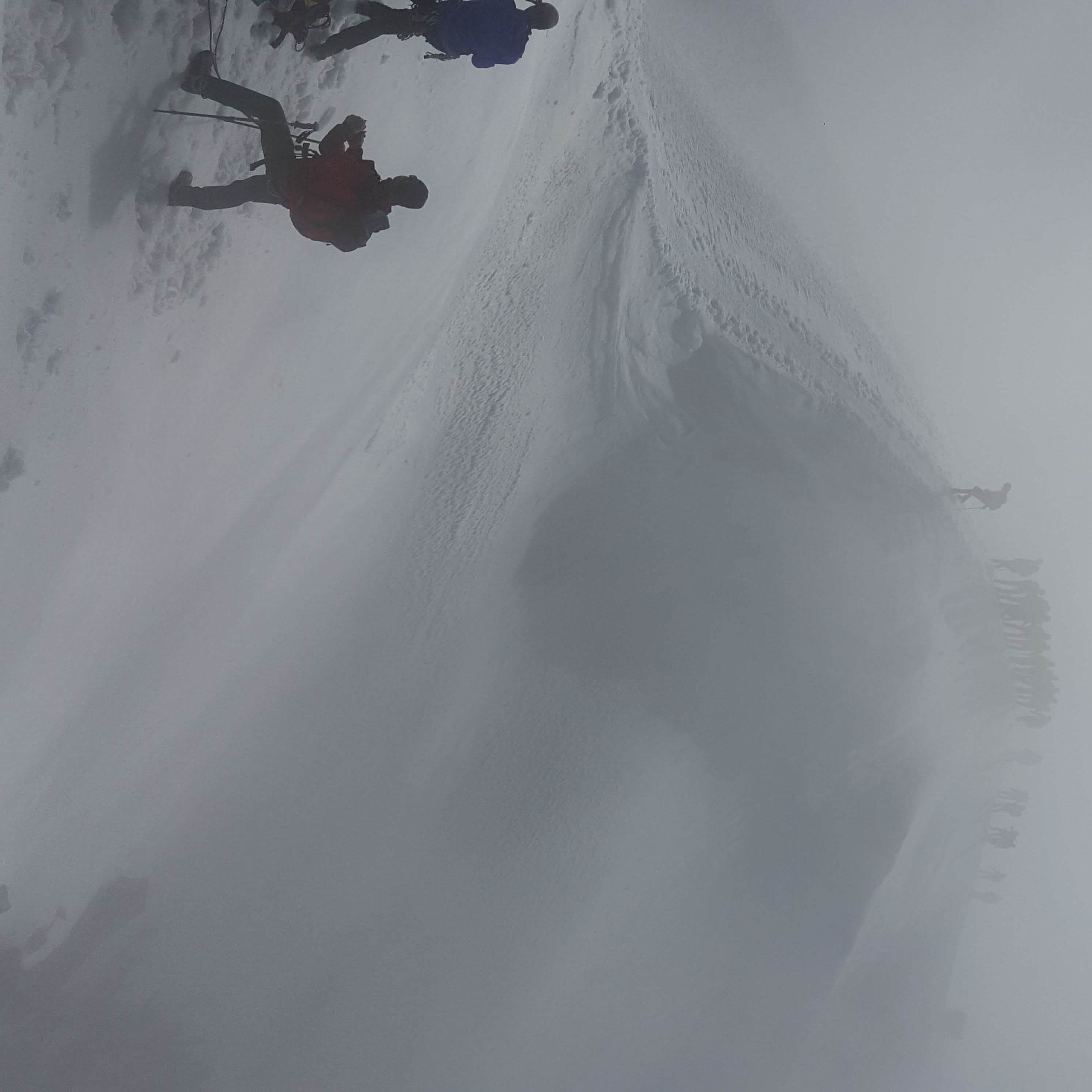A snowy landscape with a person skiing down a slope.