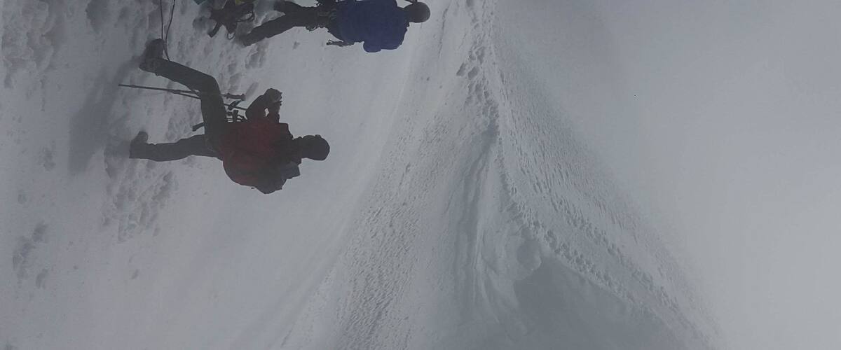 A snowy landscape with a person skiing down a slope.