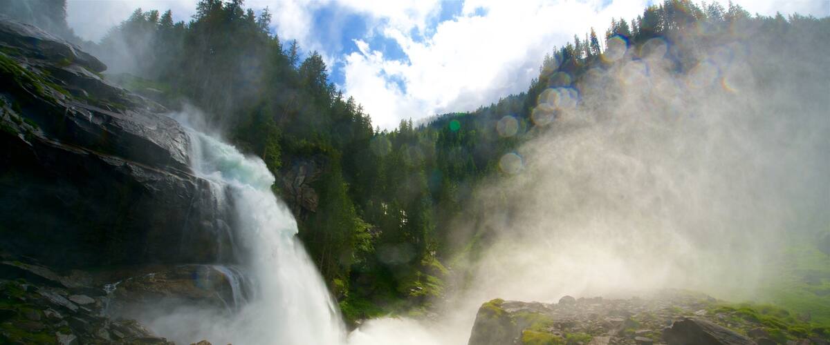 A powerful waterfall surrounded by lush greenery and rocky terrain.