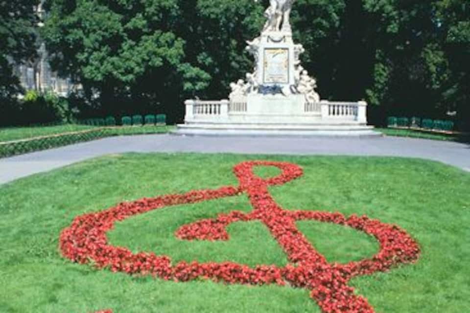 A statue in a park with a circular flower arrangement in the foreground.