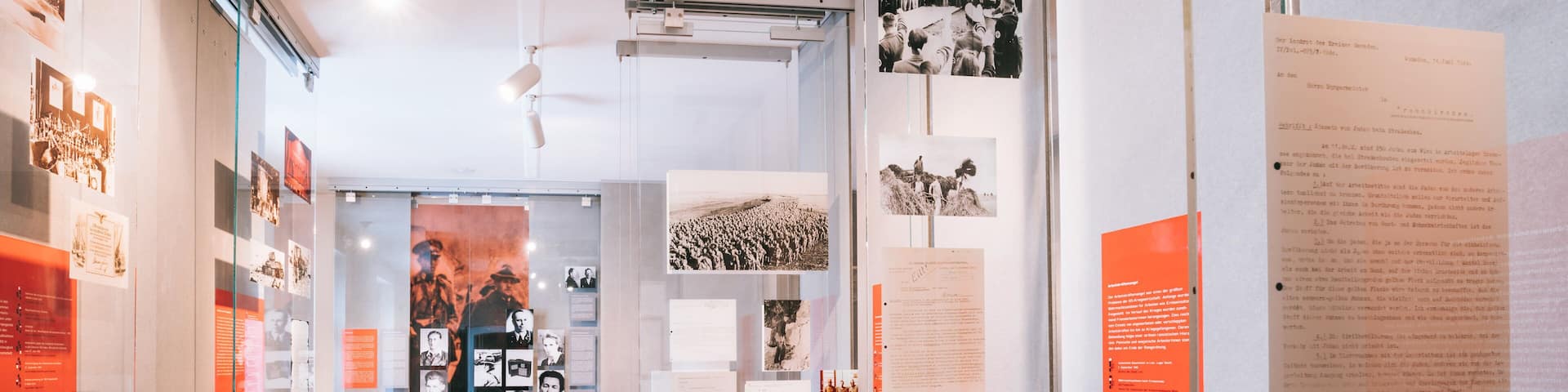 An indoor exhibition with historical photographs and documents displayed on walls and glass cases.