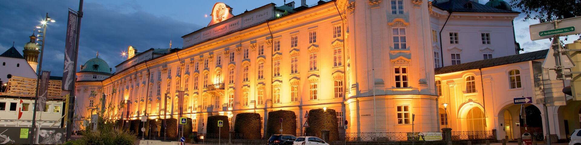 Un edificio histórico con una cúpula verde y arquitectura clásica, iluminado al anochecer.