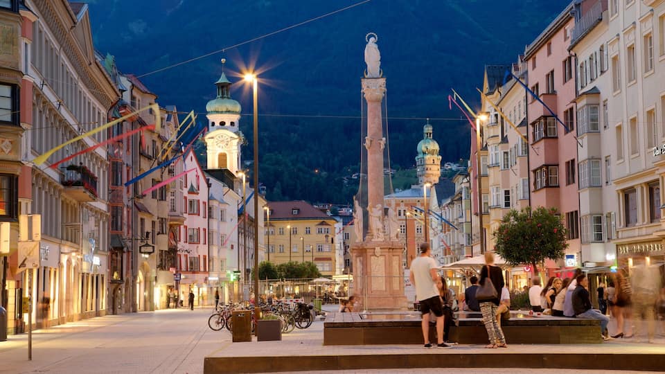 A historic square with a central monument, colorful buildings, and a clock tower in the background.