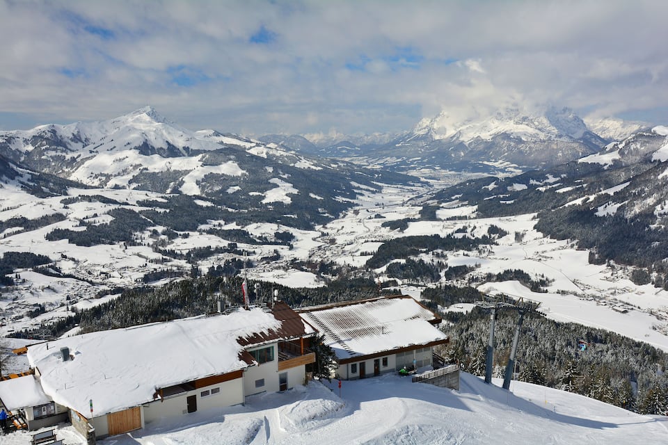 A snow-covered mountain landscape with a ski resort building in the foreground.