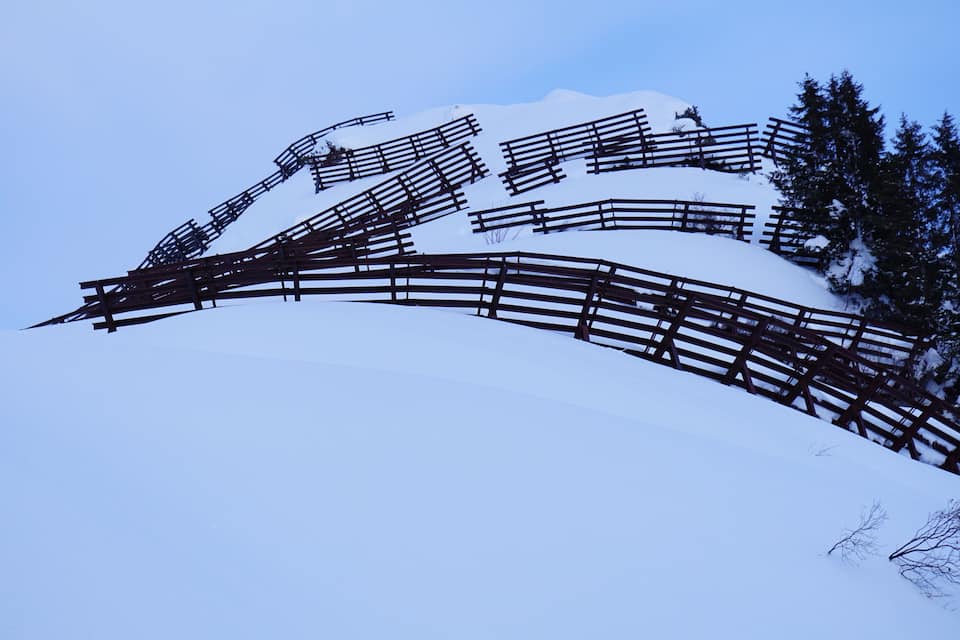 Een met sneeuw bedekte berg met een houten omheining.