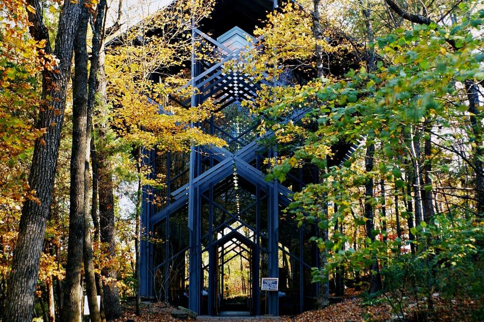 A wooden structure in a forest with autumn leaves.