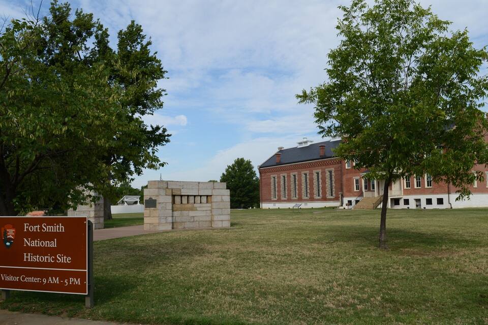 A historic site with a visitor center, a brick building, and surrounding trees.