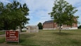 A historic site with a visitor center, a brick building, and surrounding trees.