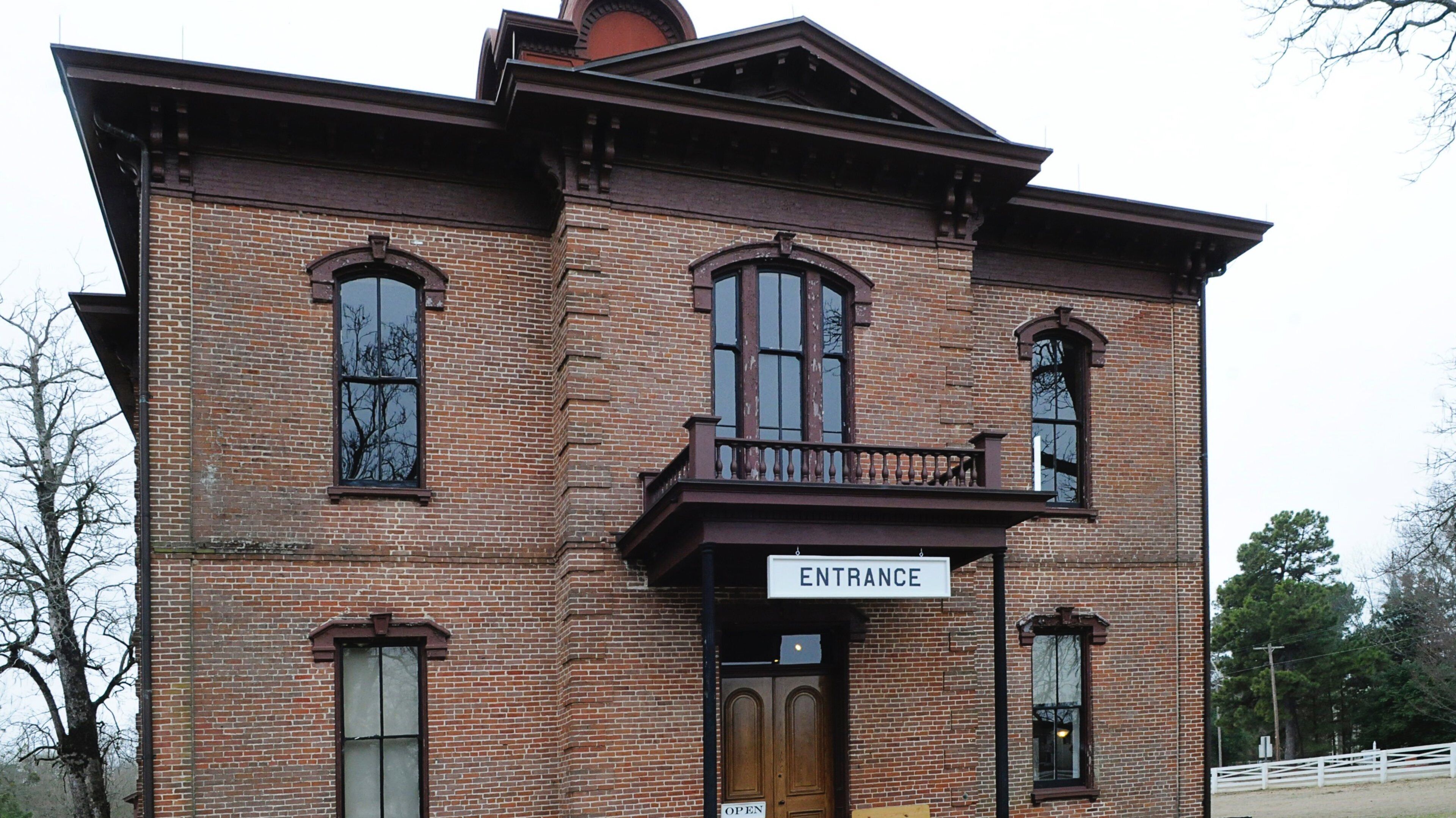 A brick building with a sign reading "ENTRANCE" above a wooden door.