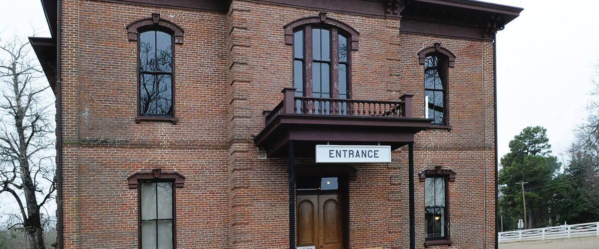 A brick building with a sign reading "ENTRANCE" above a wooden door.