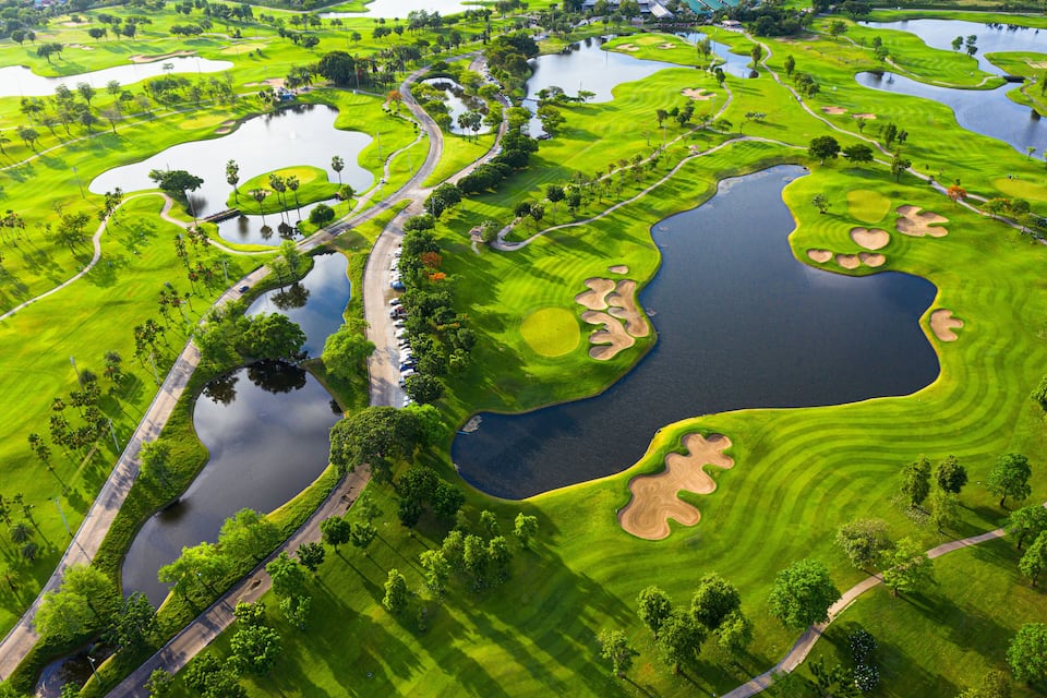 A golf course with multiple water hazards, sand bunkers, and well-maintained fairways.