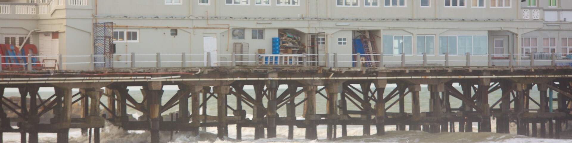 Um cais com uma placa que diz "CLUBE DE PESCA MAR DEL PLATA" e pessoas caminhando.