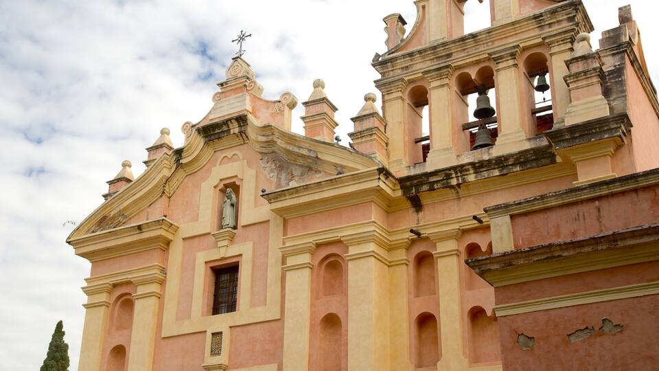 A pink church with a bell tower and a statue.