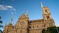 Una catedral grande con una torre del reloj destacada y arquitectura gótica intrincada.
