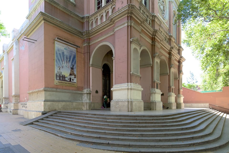 A historic building with a large arched entrance, steps leading up to it, and a poster on the wall.