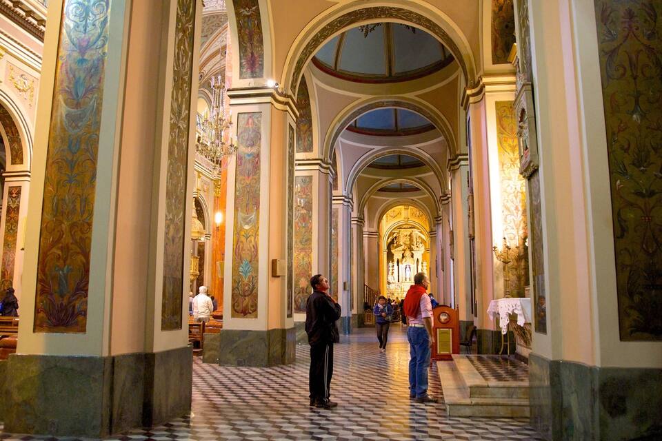 Un intérieur d’église somptueux, avec de hauts plafonds, des colonnes en arc de cercle et des fresques détaillées.
