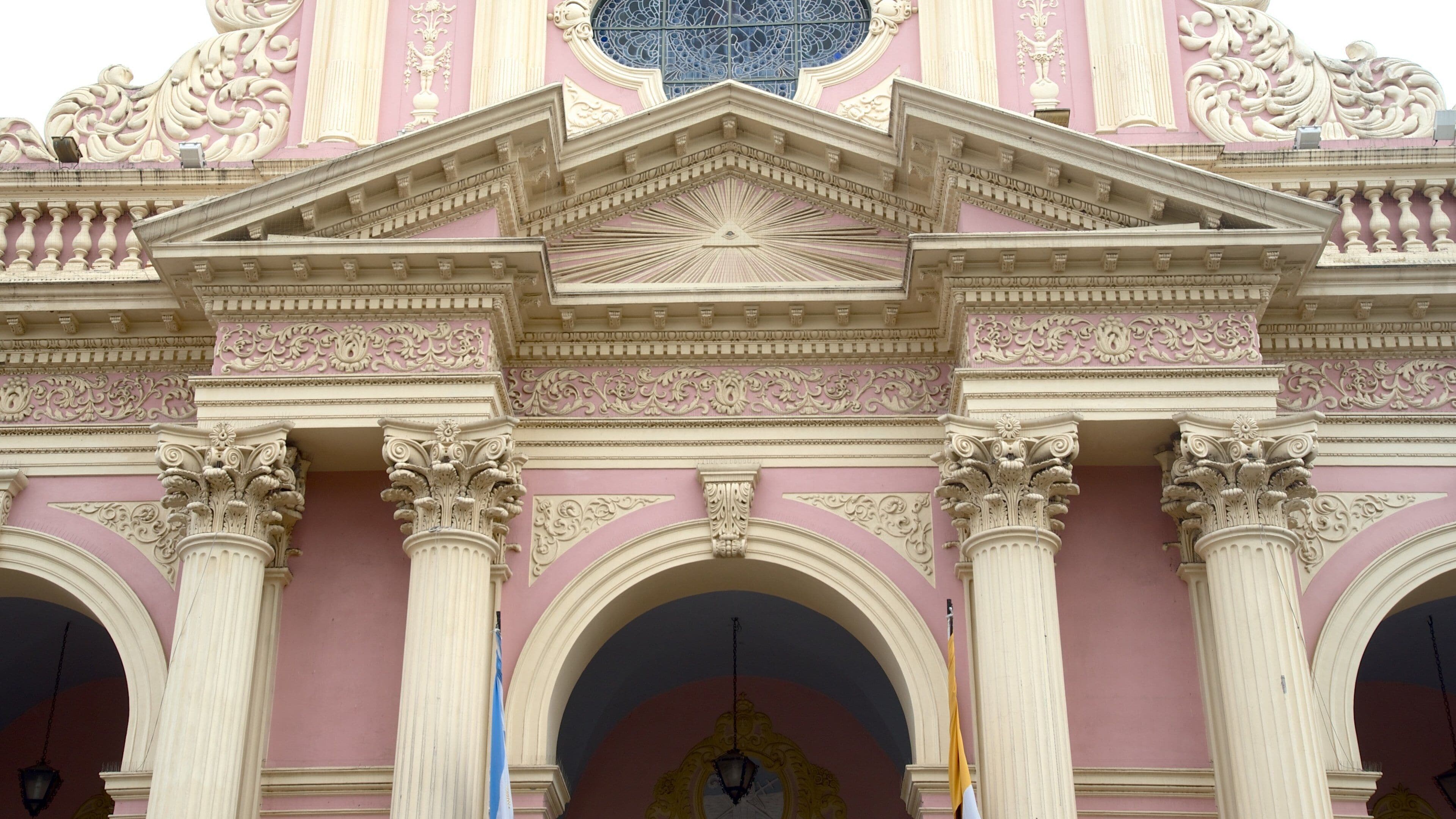 A pink building with ornate columns and a large arched entrance.
