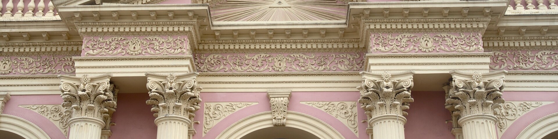 A pink building with ornate columns and a large arched entrance.
