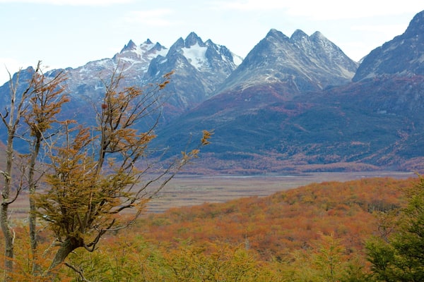 A mountainous landscape with autumn-colored trees and snow-capped peaks.