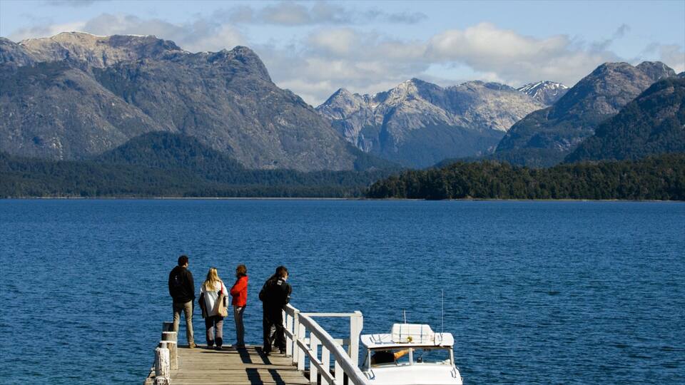 A wooden pier extending into a lake with mountains in the background.