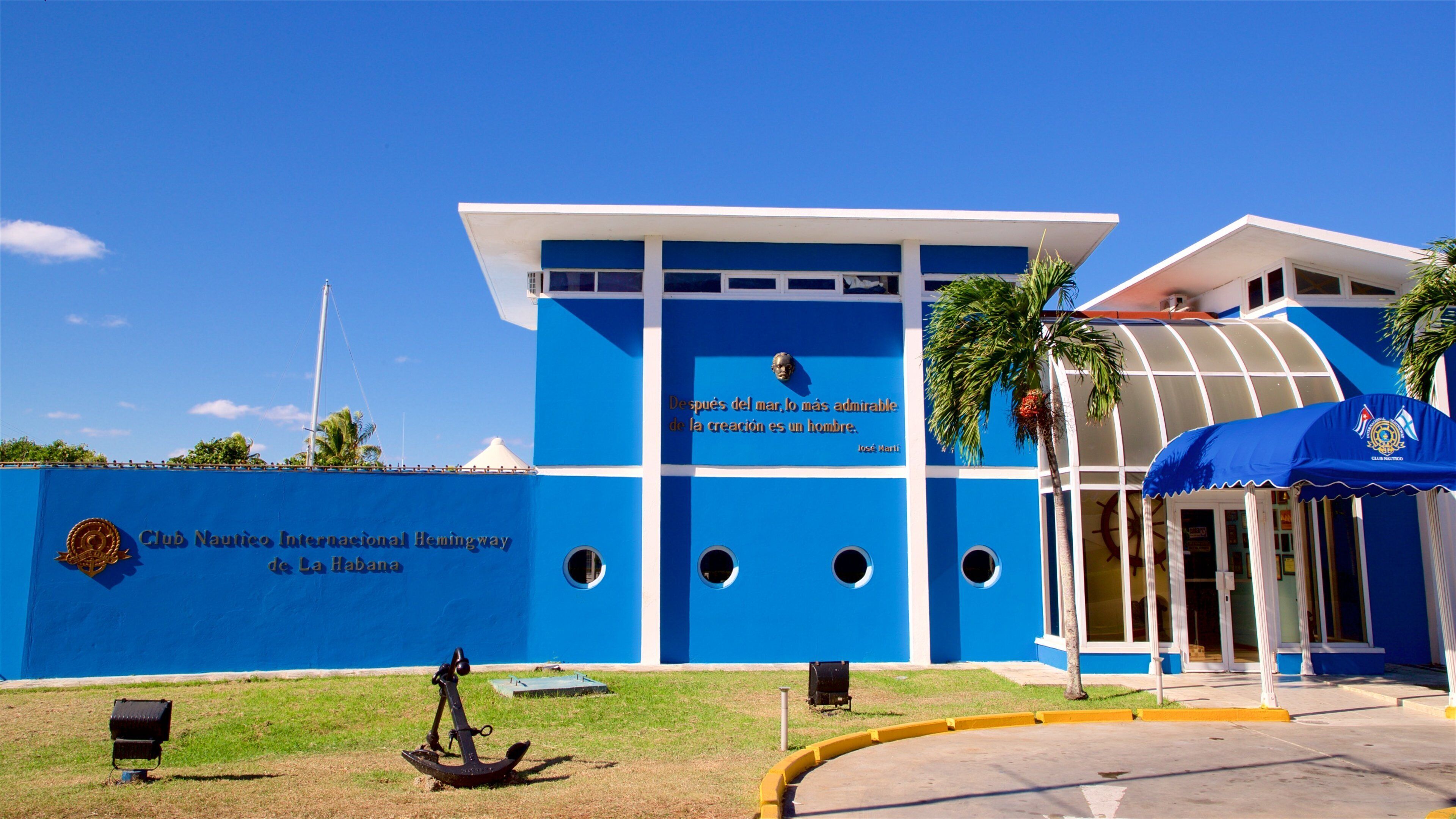 Club Nautico Internacional Hemingway de La Habana with a blue facade, an anchor sculpture, and a quote by Jose Marti.