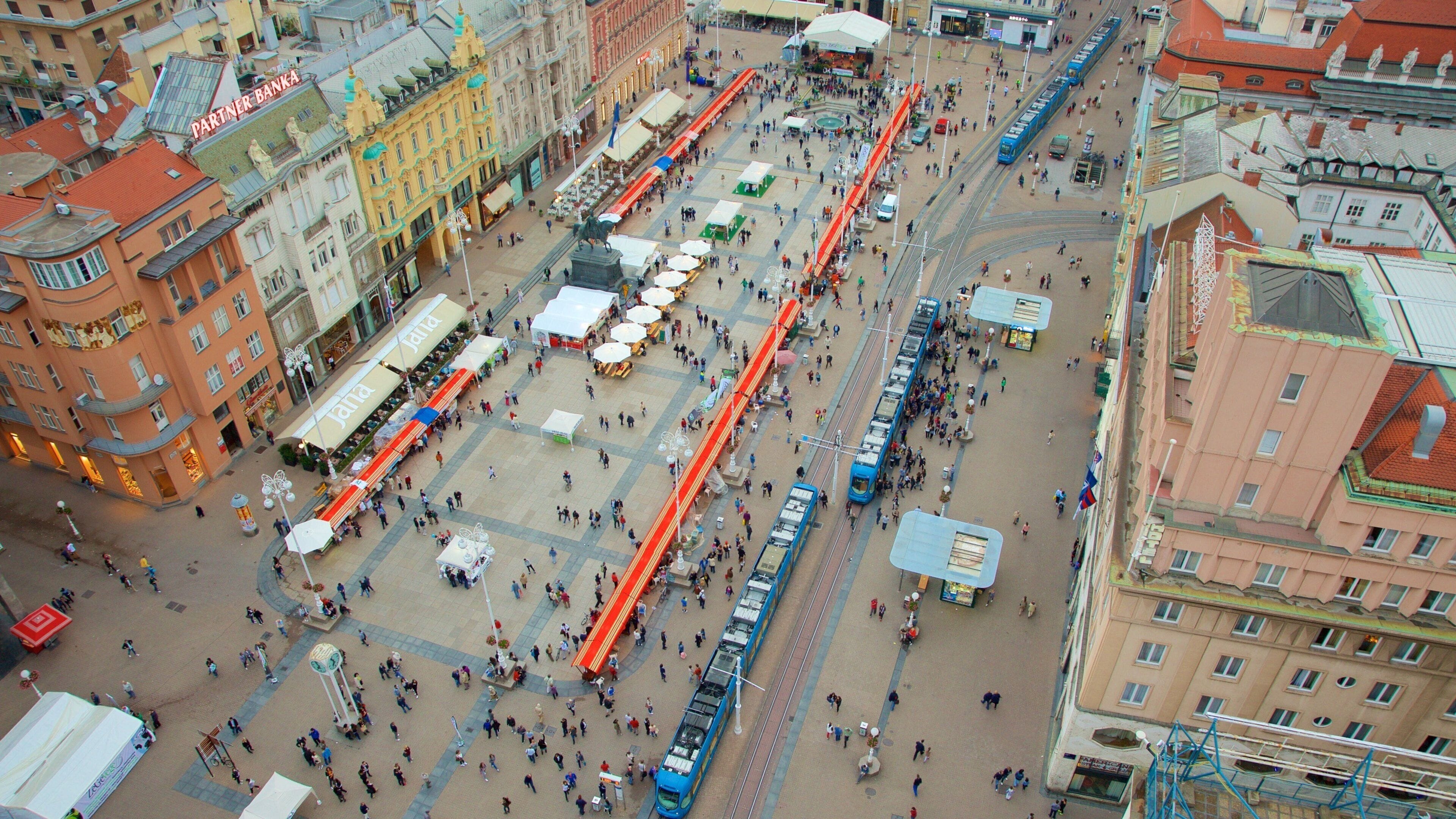 A bustling square with tram lines, historic buildings, and outdoor cafes.