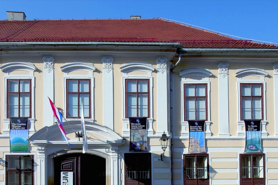 A historic building with a red-tiled roof and multiple banners hanging from the windows.
