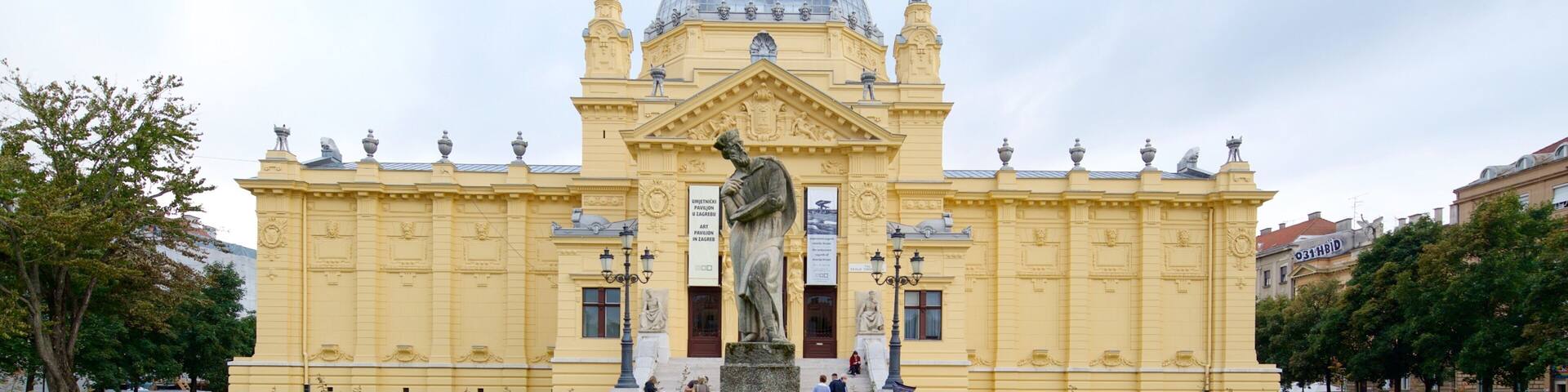 A large yellow building with a statue in front.