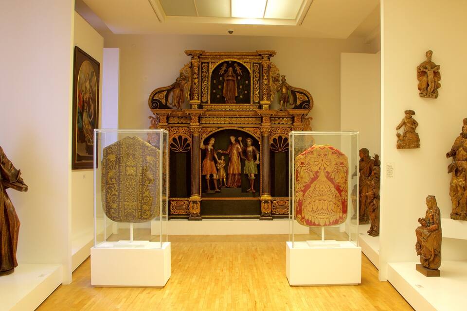 Interior de museu amb escultures de fusta i un altar central ornamentat.