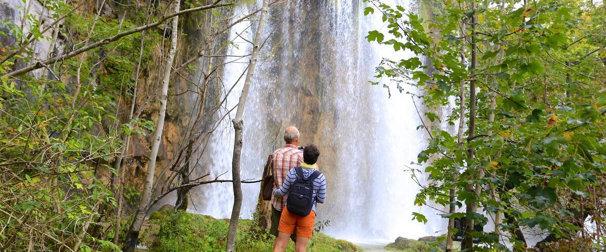 A waterfall with a wooden bridge leading to it.