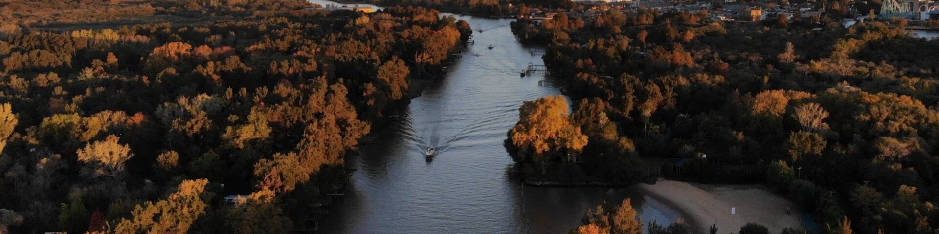 A river winding through a densely wooded area with autumn foliage, surrounded by urban development.
