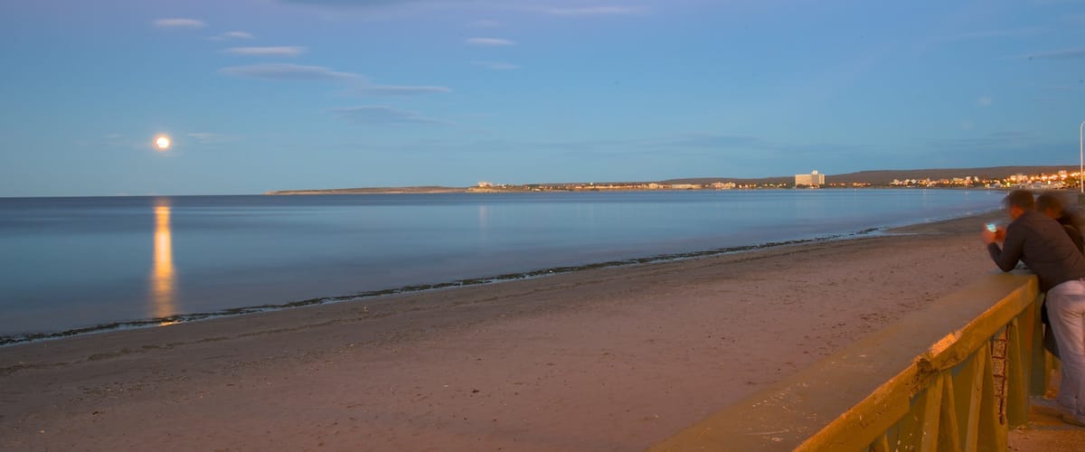 Puerto Madryn Beach which includes general coastal views, a sunset and a sandy beach