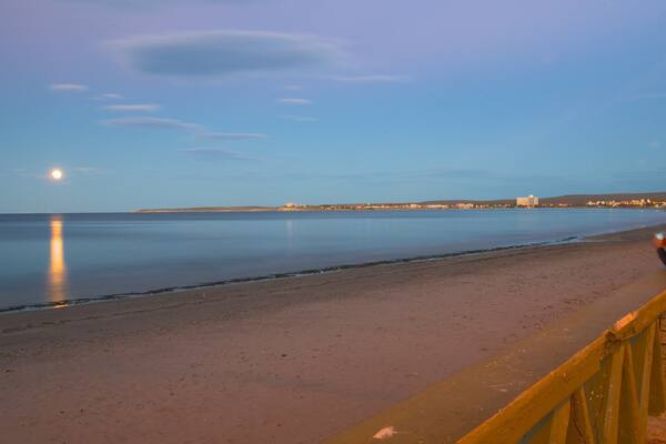 Puerto Madryn Beach which includes general coastal views, a sunset and a sandy beach