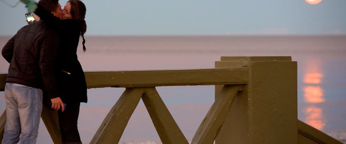 Puerto Madryn Beach featuring a sunset as well as a couple