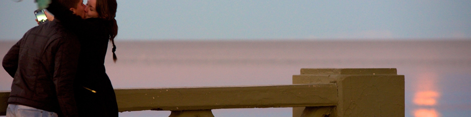 Puerto Madryn Beach featuring a sunset as well as a couple